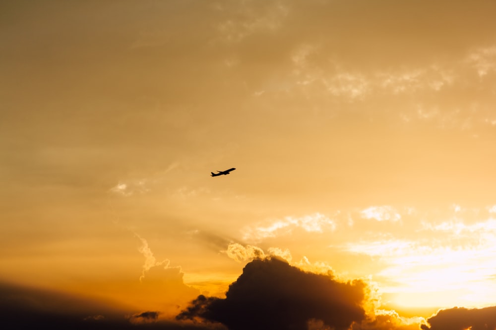 plane over black clouds in orange sky