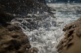 time lapse photography of water making bubbles as it hits the rocls