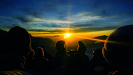 A sunrise hike with men silhouetted against the glowing horizon, symbolizing new beginnings.