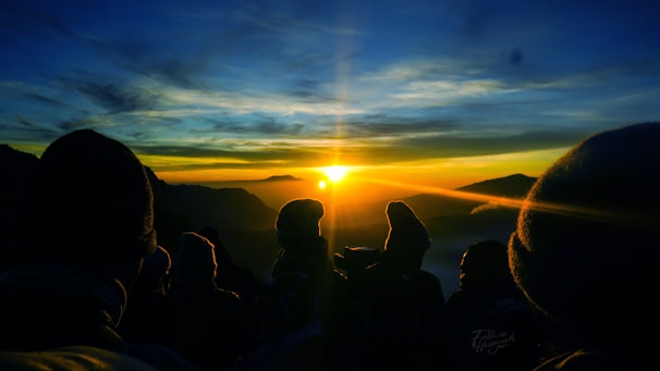 A person standing on a mountain peak at sunrise, symbolizing achievement and new beginnings.