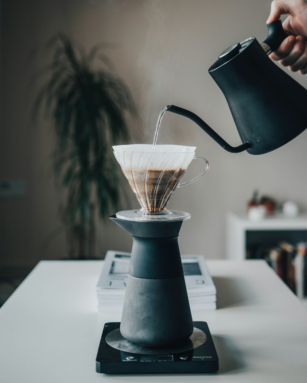 person pouring hot water on pour-over coffee maker