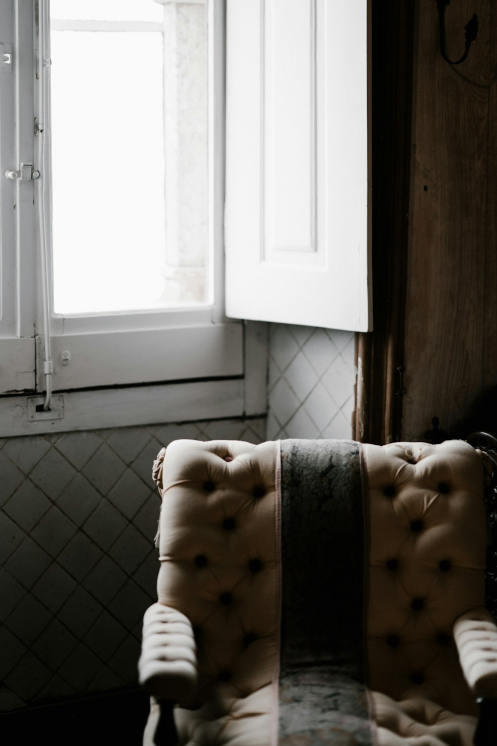 empty tufted brown fabric sofa armchair near window