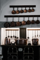 assorted cooking pots and pans hangs over black cast iron stove