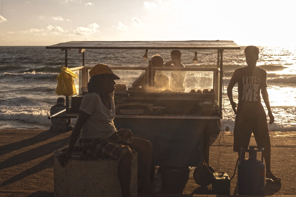 woman sitting beside food cart near beach