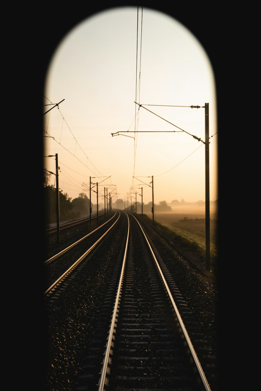 Fotografía de enfoque selectivo del ferrocarril del tren bajo el cielo blanco durante la hora dorada