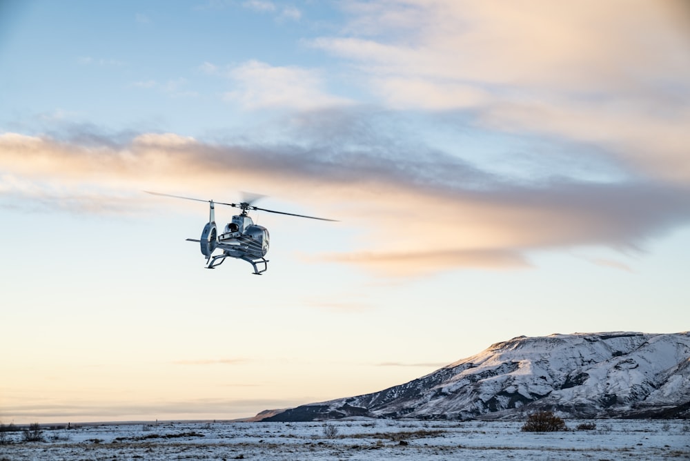 helicopter flies over snow covered tundra