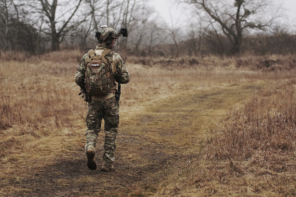 hombre que camina sobre un campo de hierba marrón