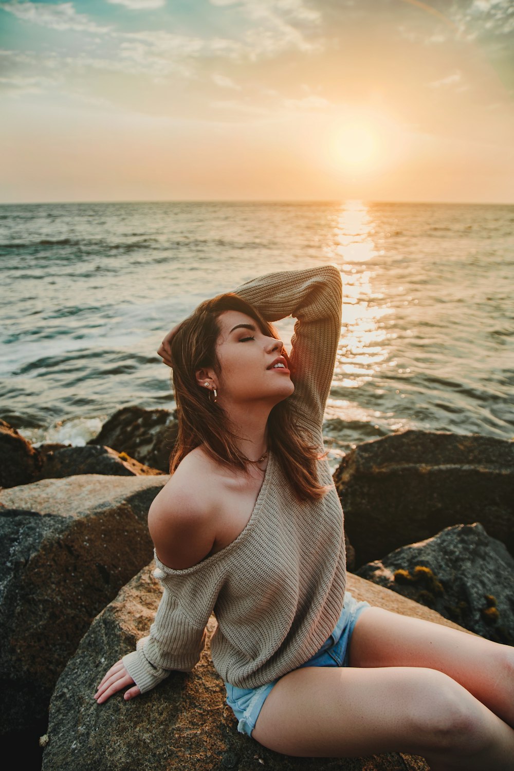 woman sitting on rock near sea water