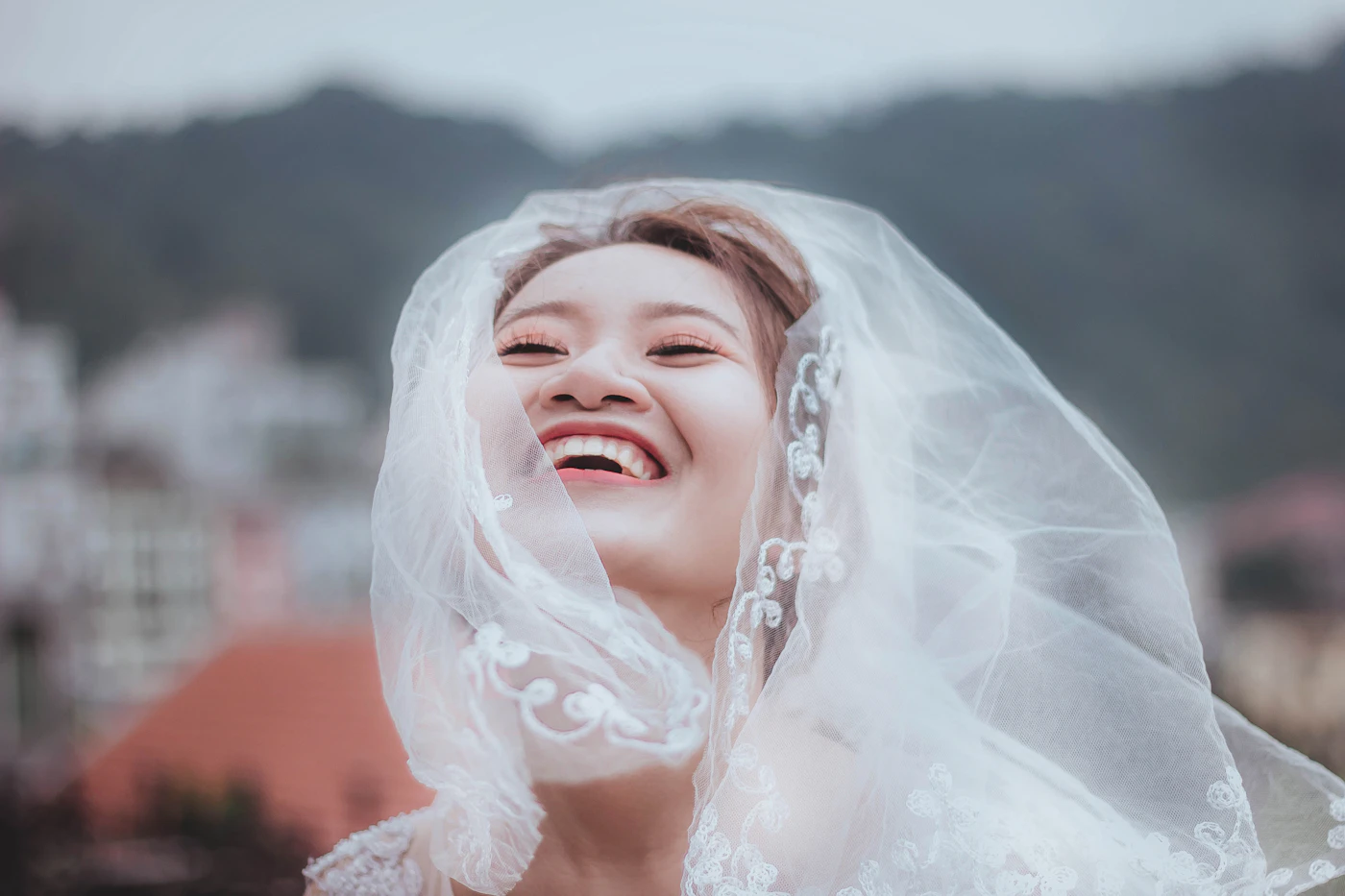 How to sew your own wedding veil — A close-up of hands gathering tulle fabric with a needle and thread on a sewing table.