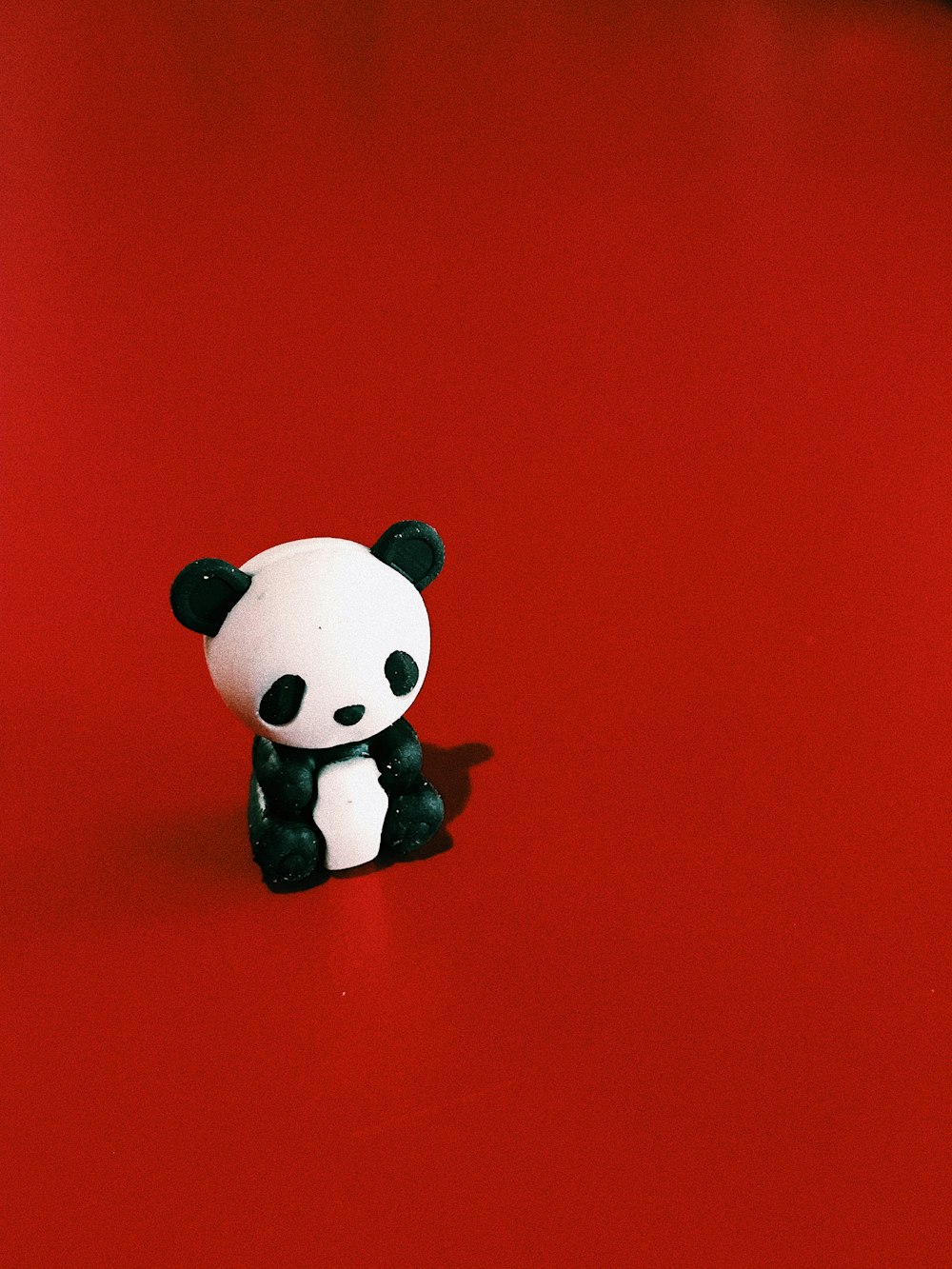 panda bear figurine sitting on red surface