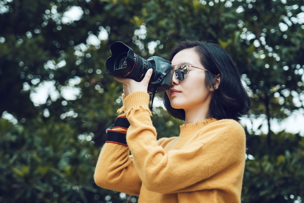 Mujer tomando foto cerca de un árbol