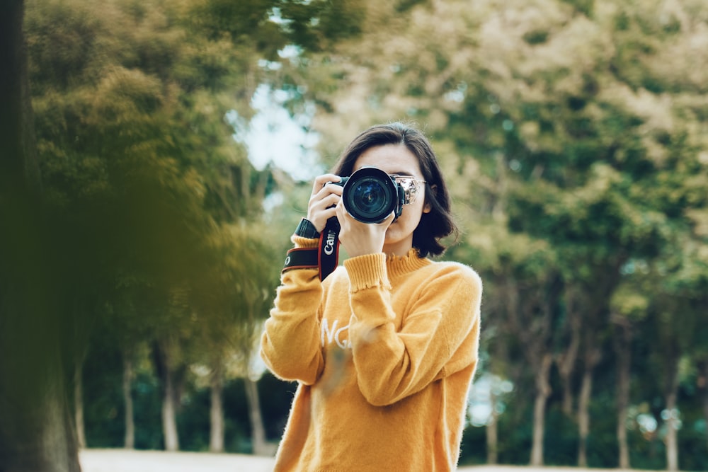 femme tenant un appareil photo reflex numérique