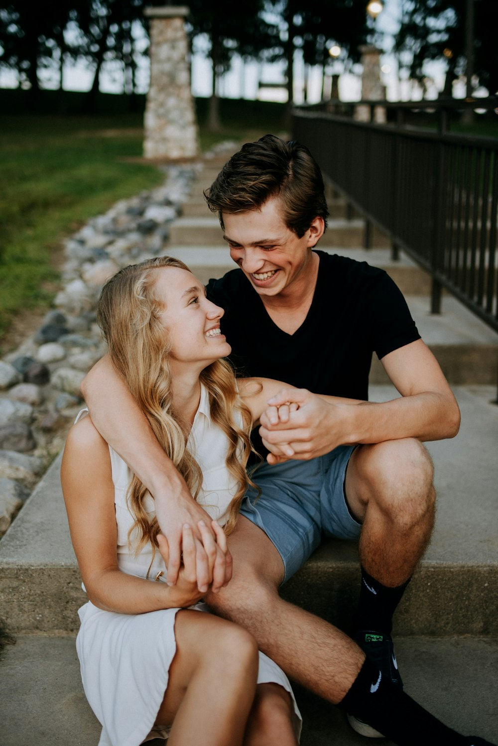 man holding the hand of a woman while siting on concrete staircase