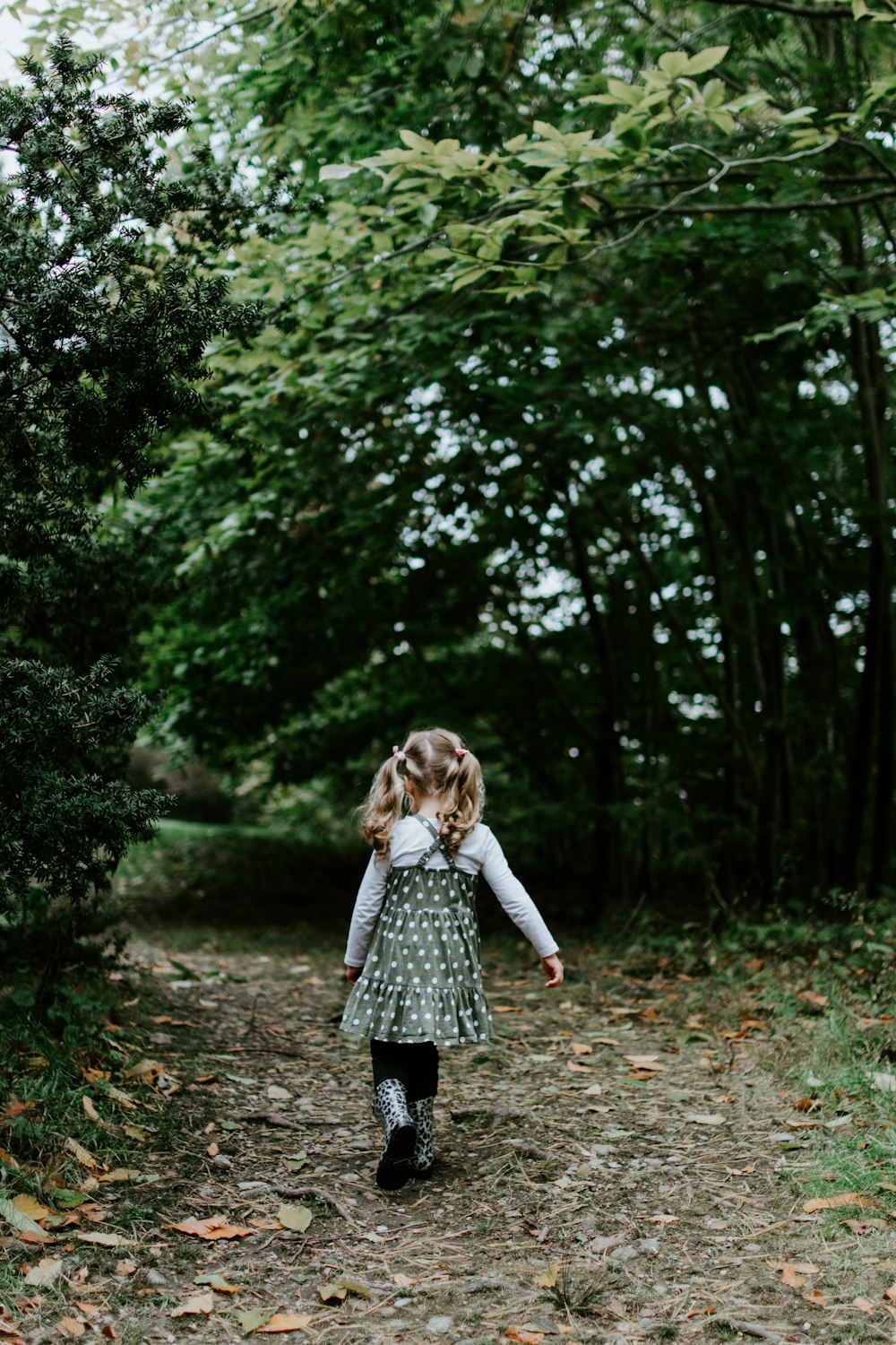 緑の葉の木々の近くを歩く女の子