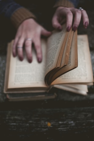 Close-up of hands carefully repairing an old book's spine with delicate tools.