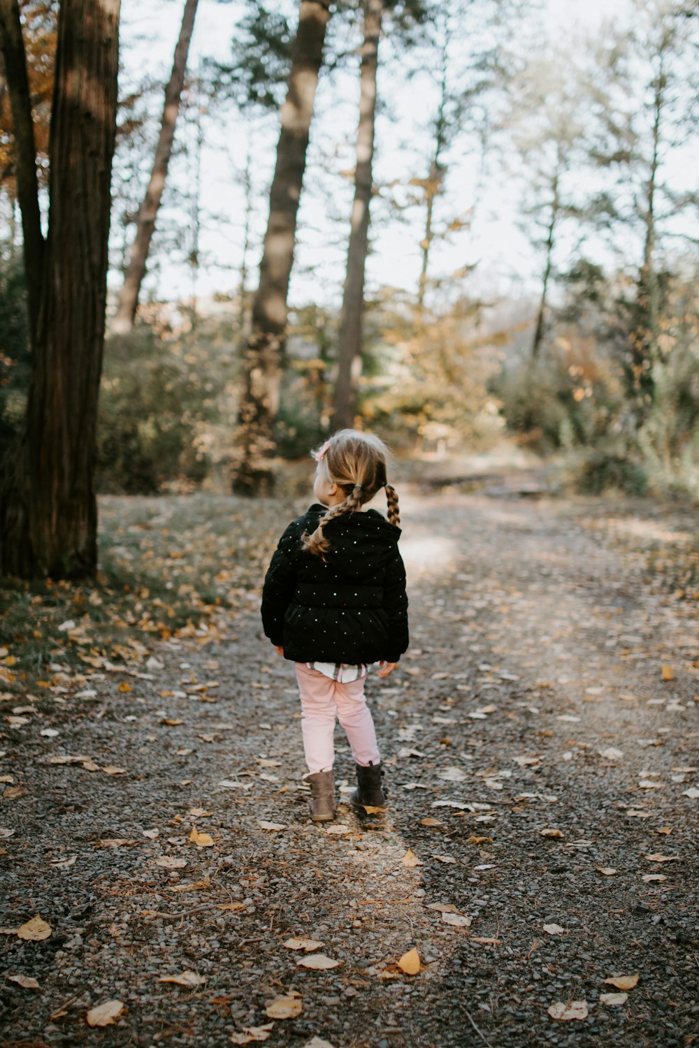 Chica con chaqueta negra caminando en el bosque