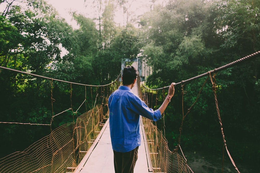 man standing on yellow and brown hanging bridge