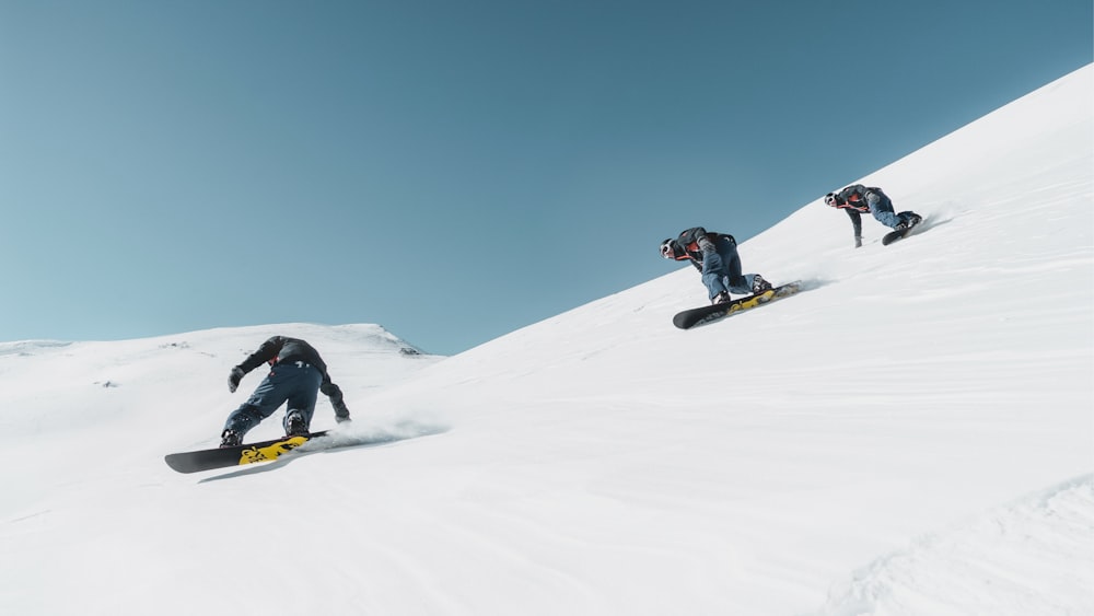 trois personnes à cheval sur le snowboard