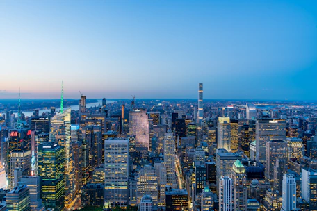 A panoramic city skyline at dusk showcasing international financial centers under a clear blue sky.