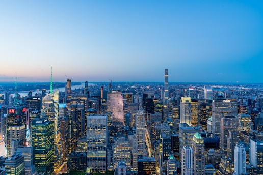 A panoramic view of a bustling international financial district at dusk, with skyscrapers glowing in burgundy and red hues.