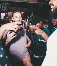 three people holding glass bottles while talking