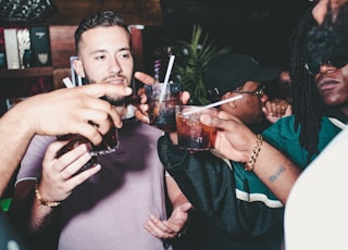 three people holding glass bottles while talking