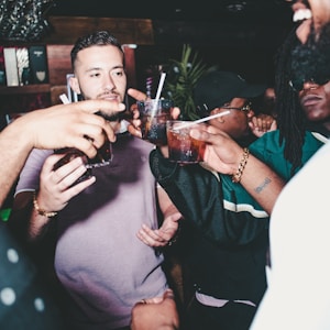 three people holding glass bottles while talking