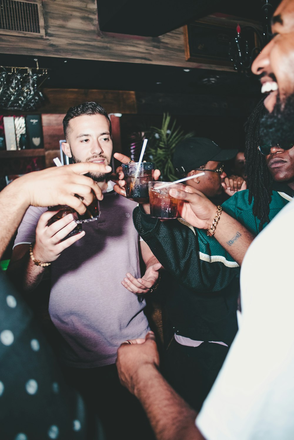 three people holding glass bottles while talking