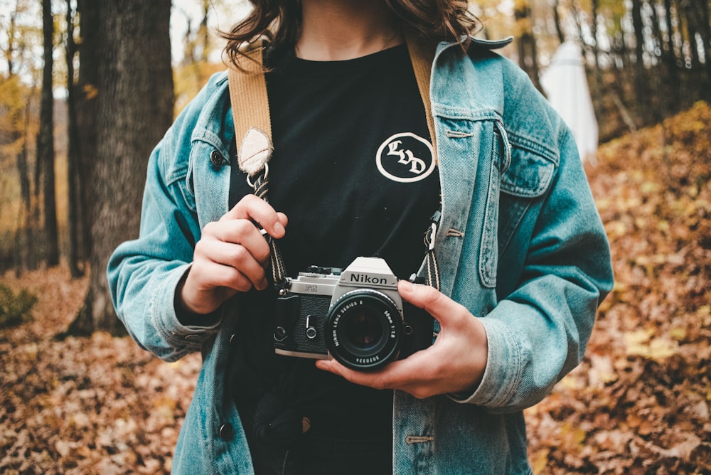 woman holding gray Nikon camera