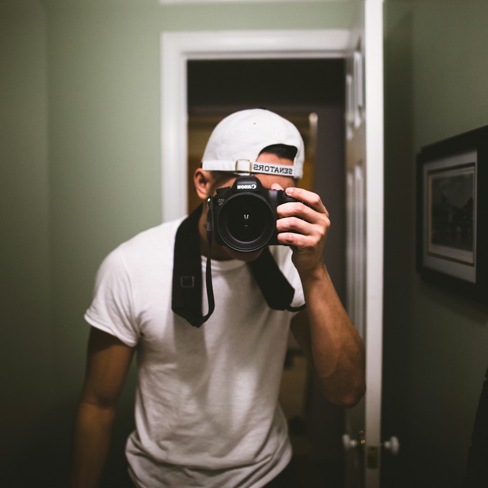 man taking a photo using black DSLR camera