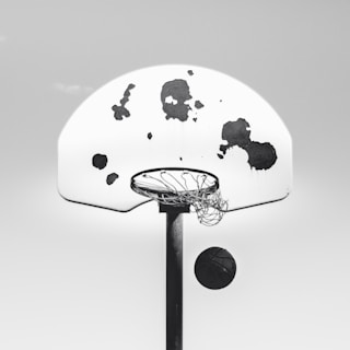 A street basketball hoop with a well-worn ball showing signs of hours of play, capturing street entertainment spirit.