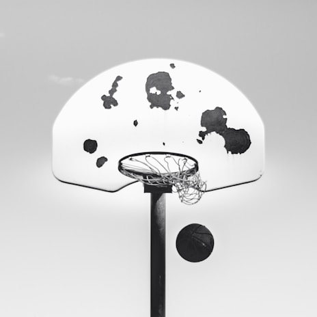 A street basketball hoop with a well-worn ball showing signs of hours of play, capturing street entertainment spirit.