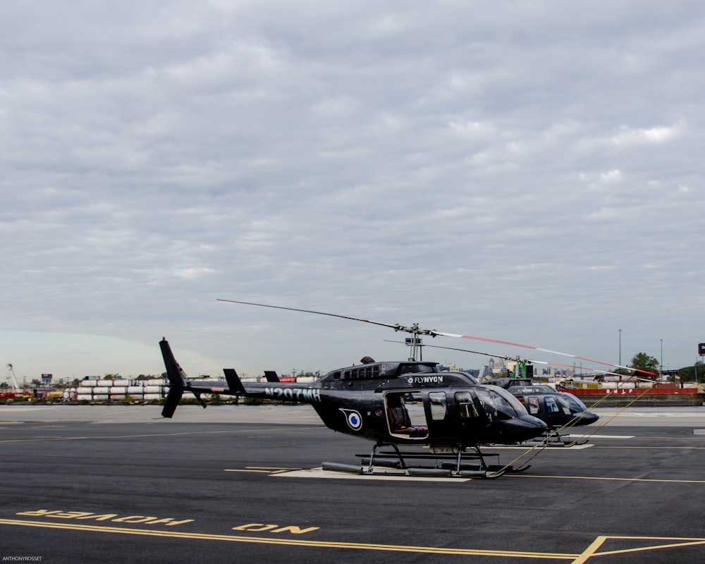 two black helicopters near on concrete pavement
