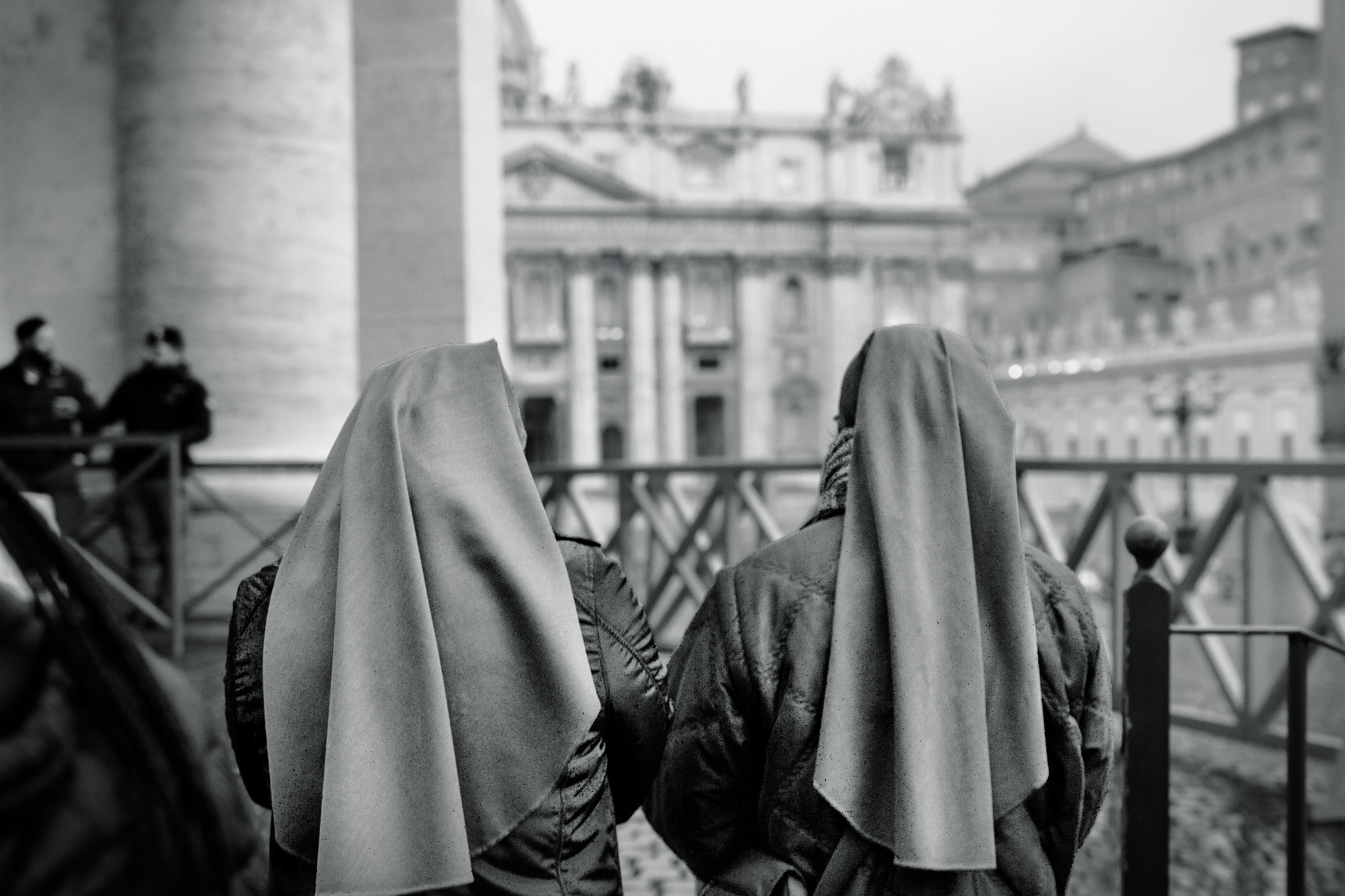 grayscale photography of two women near fence