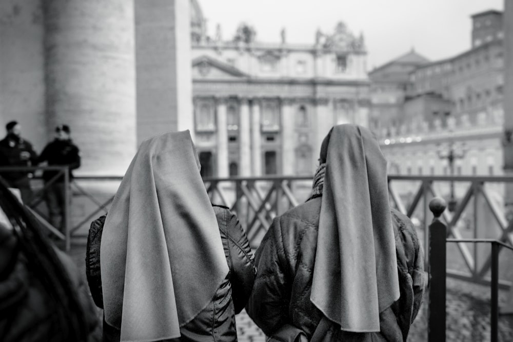 grayscale photography of two women near fence