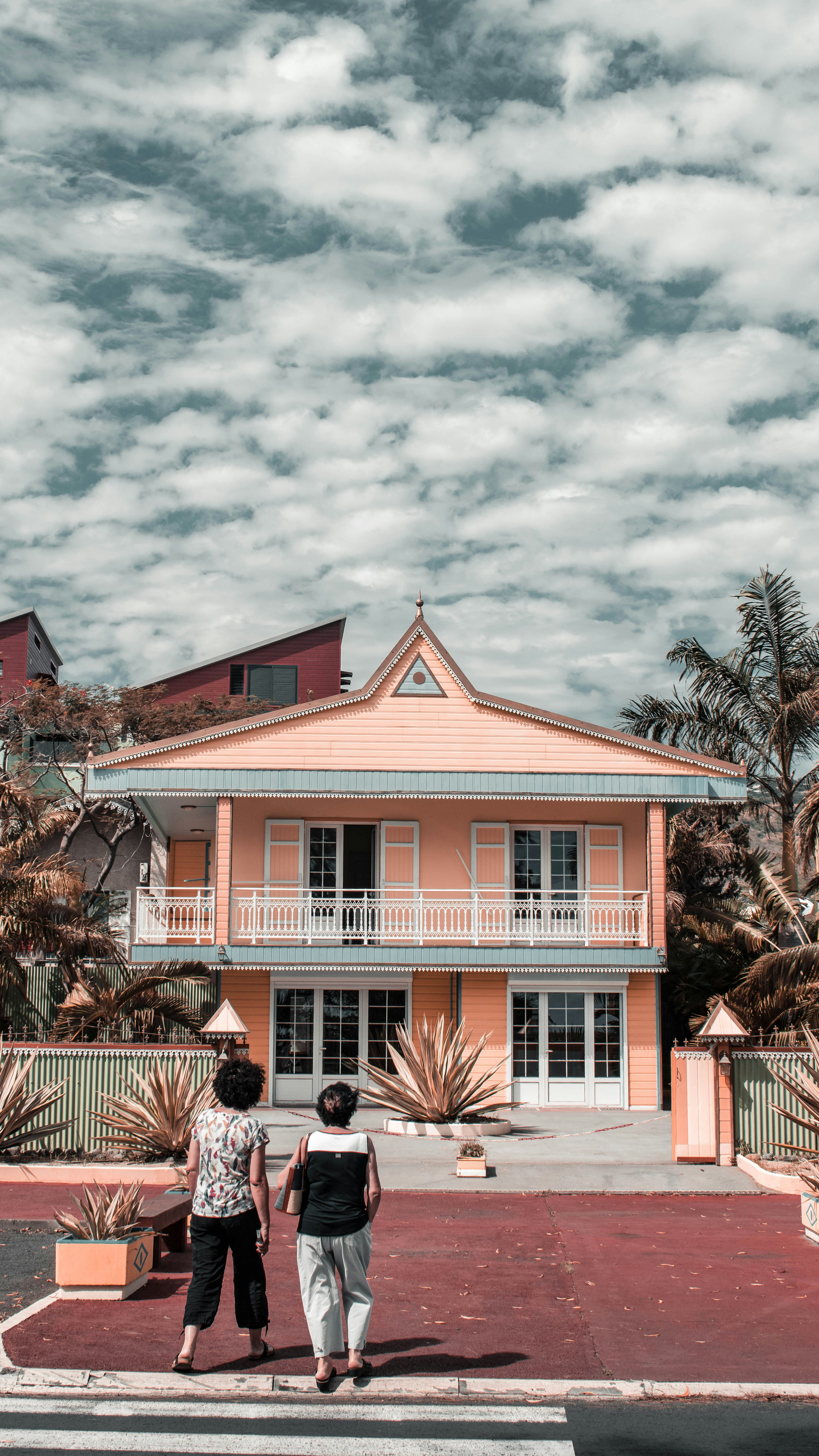 two women in front of peach-painted 2-storey house