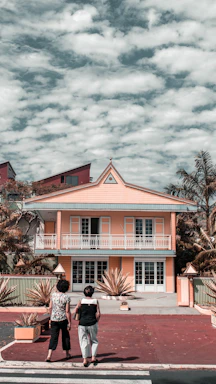 A warm, inviting photo of Payal Patel and Amie Arbid smiling in front of a beautiful Coachella Valley home.