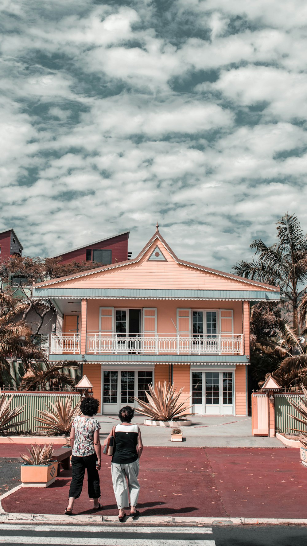 two women in front of peach-painted 2-storey house