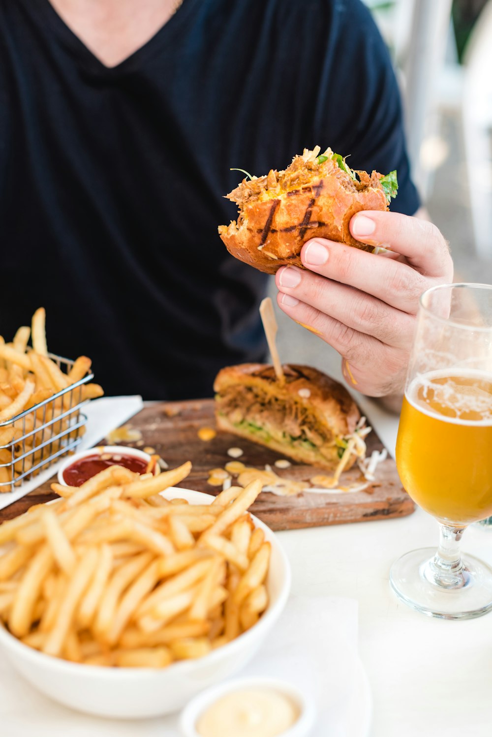 personne tenant du pain dans des fruits de frites frites sur une table blanche