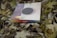 A square book or album with a multicolored spine, marked 'Instagram', rests on a bed of dried leaves. The cover of the book features a circular design with wooden and light textures.