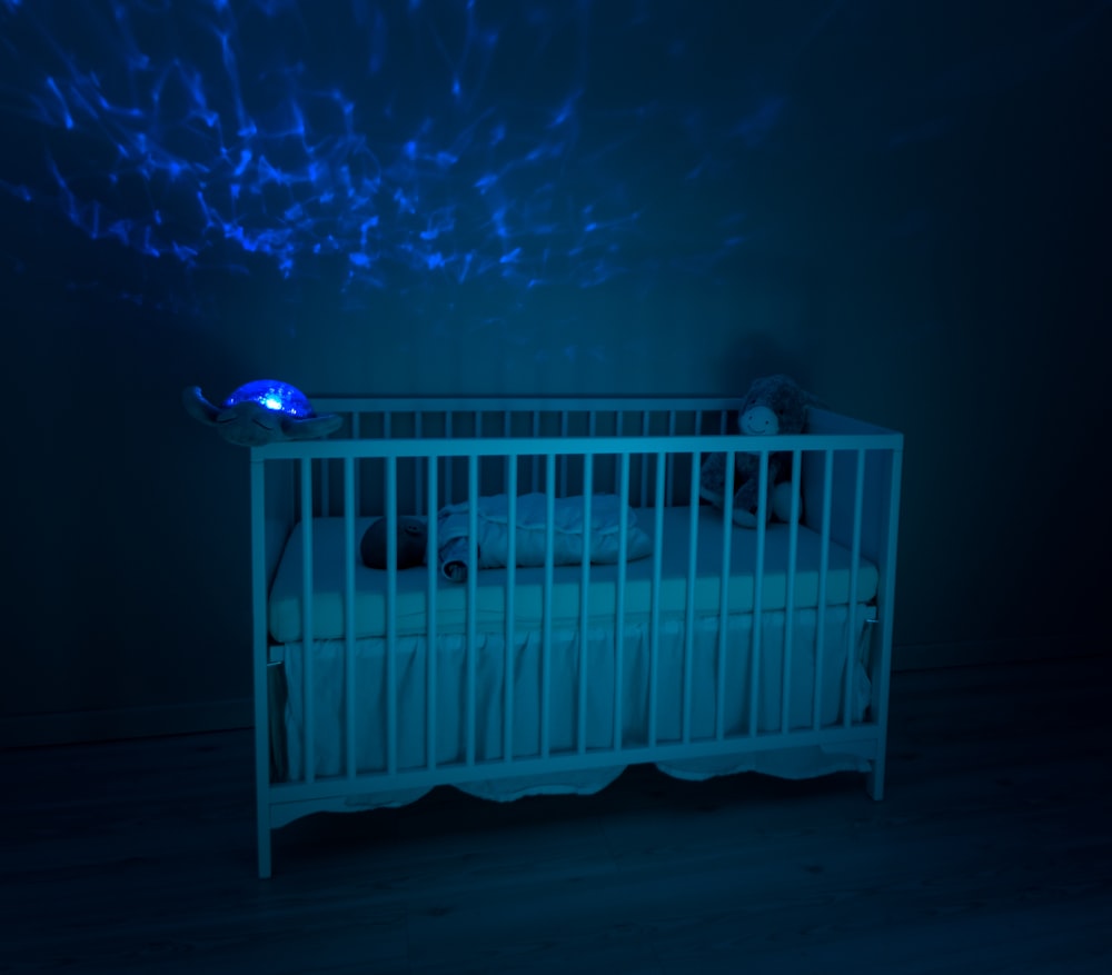 baby's white wooden crib lowlight photography