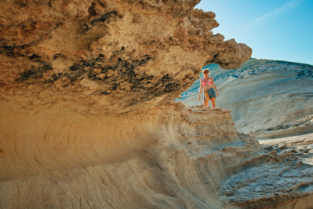 woman standing near brown rock formation under clear blue sky