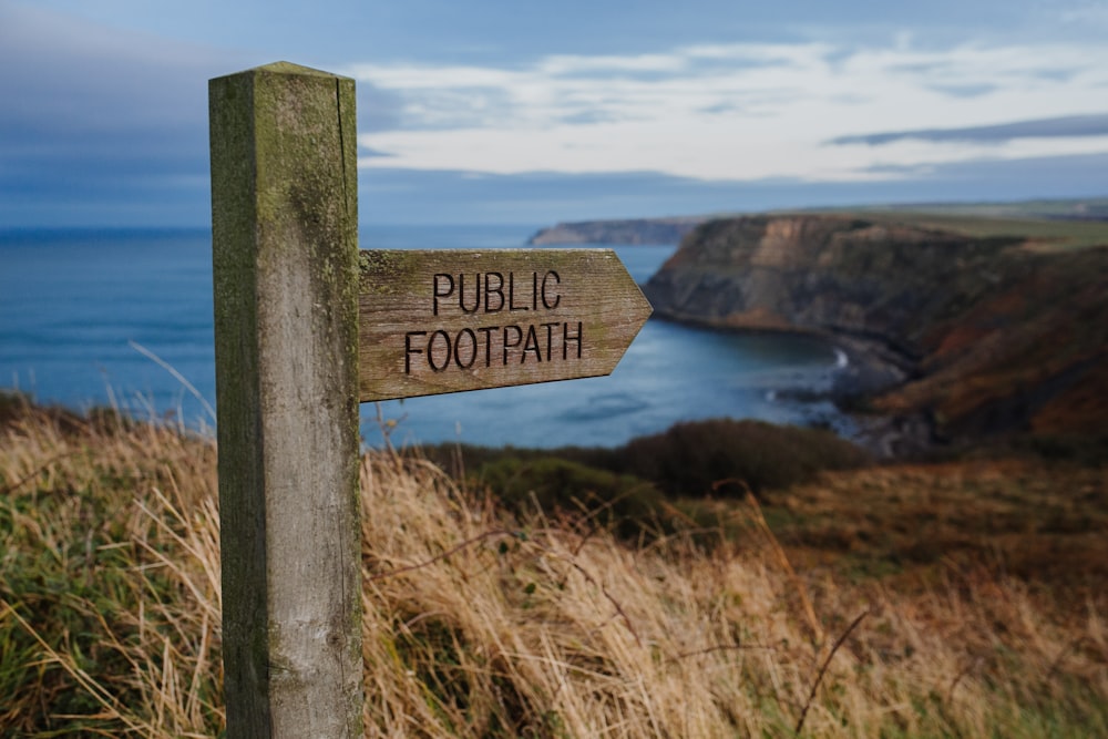 Public Footpath concrete road signage surrounded by grass during daytime