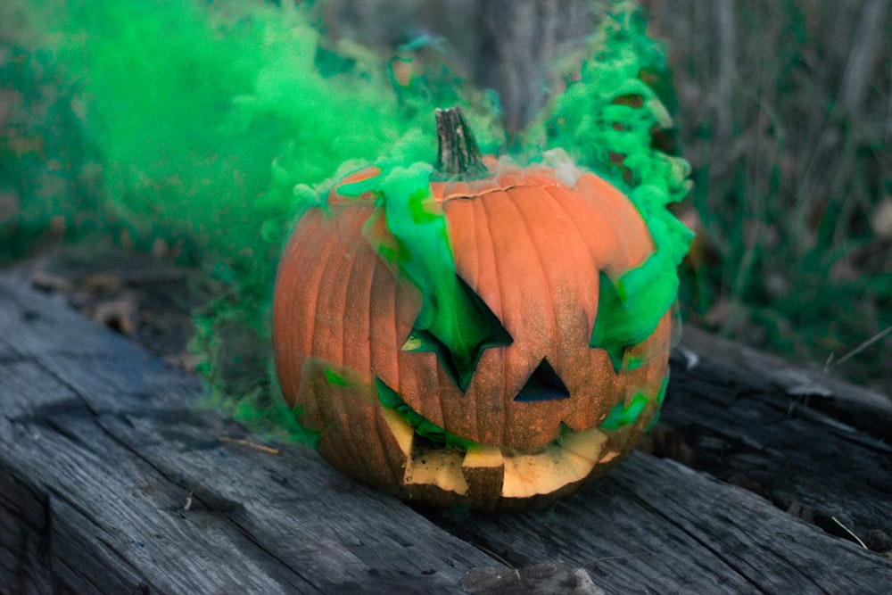 Jack-o'-lantern liberando humo verde sobre tabla de madera gris