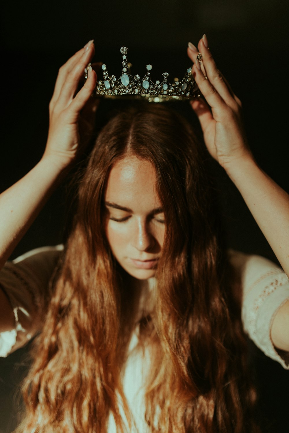 woman putting silver-colored tiara on her head