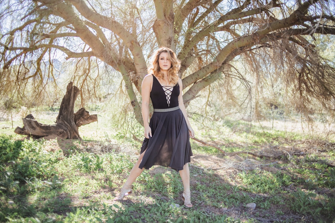 woman in black dress standing in front of tree