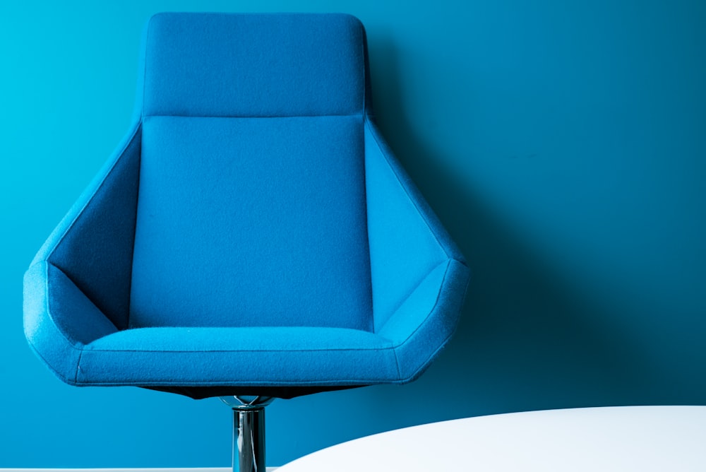 blue padded swivel chair leaning on wall