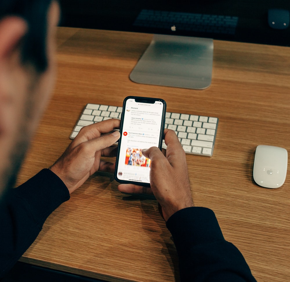 man holding phone while leaning on table