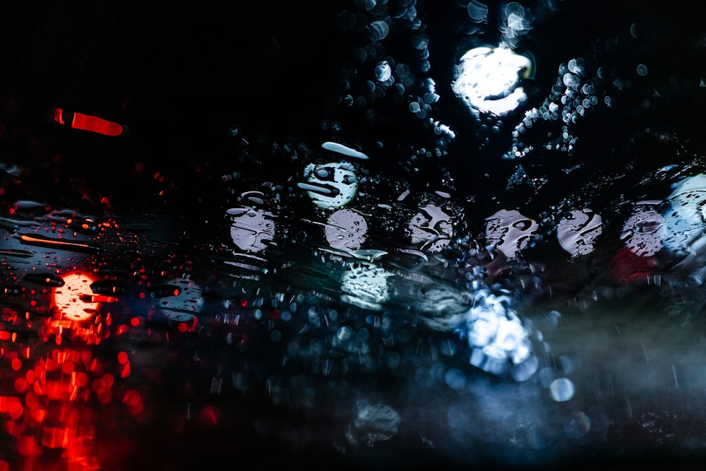 a picture of a rain covered windshield with a clock in the background