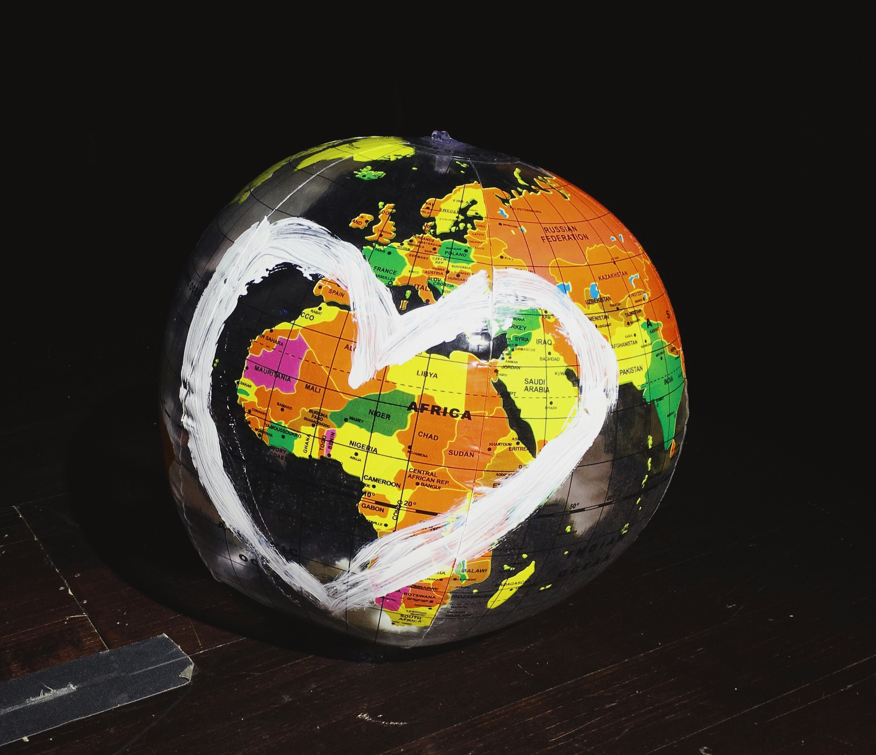 orange, green, and yellow globe on brown wooden surface